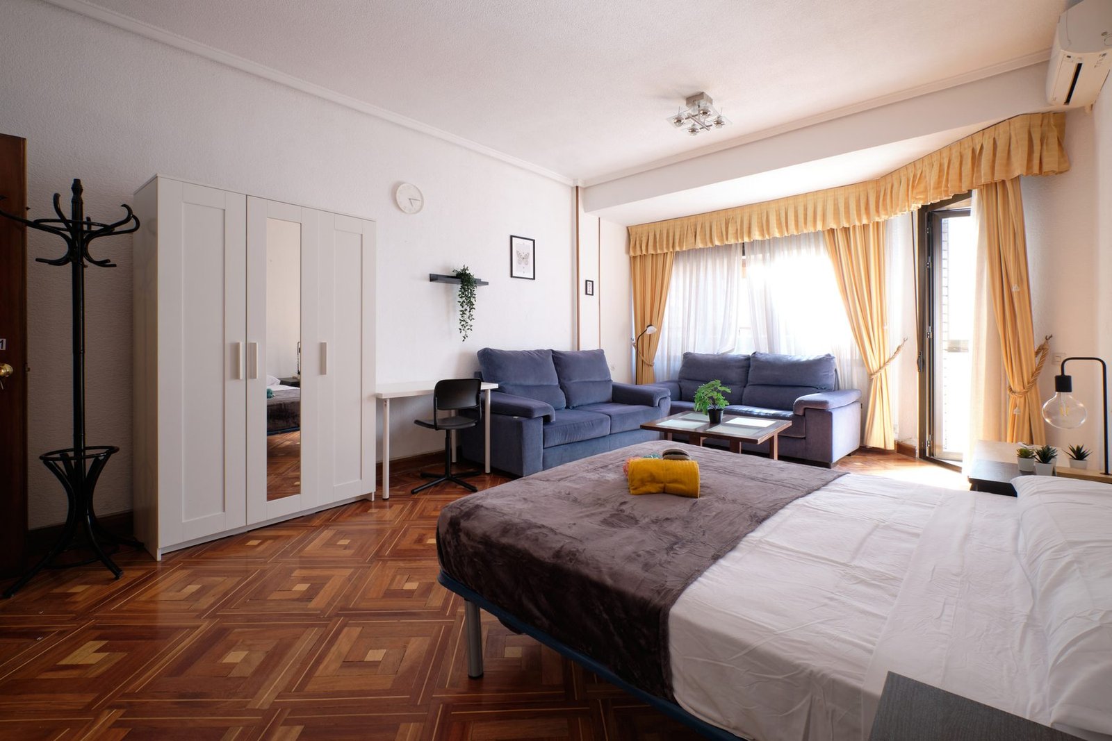 Salón amplio de una vivienda gestionada por Verantia, con sofás, armario de espejo y balcón
