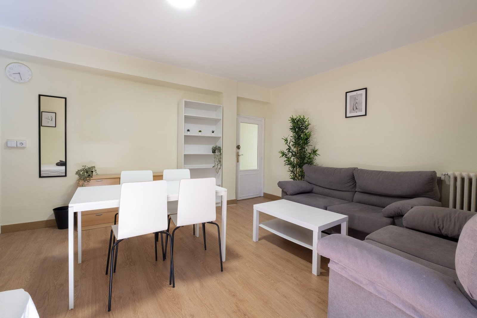 Salón amplio de una vivienda gestionada por Verantia, con sofá, mesa de comedor blanca y mucha luz natural